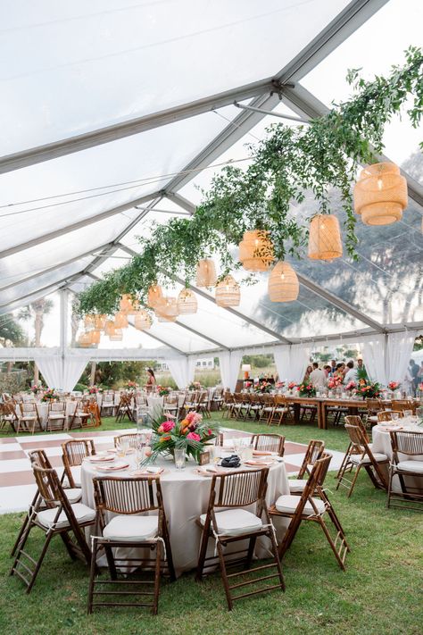 Following the ceremony, guests were greeted under a clear tent with vibrant signature cocktails and delicious hors d'oeuvres. Rattan lanterns and greenery hung above the checkered dance floor where everyone gathered to watch the first dances take place. #weddingtables #weddingtent #weddinglamps #weddings Wicker Lanterns Wedding, Tropic Wedding, Outdoor Wedding Tent, Checkered Dance Floor, Rattan Lighting, Clear Tent, Signature Cocktails, Custom Koozies, Wedding Lanterns