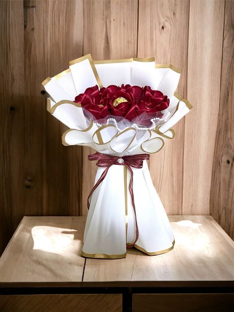 We are offering an elegant and beautiful Ferrero Rocher  roses bouquet. The bouquet contains 7 handmade satin roses combined with Ferrero Rocher, which can be kept as a memory for many years to come. Satin Roses Bouquet, Satin Flower Bouquet, Rocher Bouquet, Ferrero Rocher Bouquet, Satin Bouquet, Ribbon Flowers Bouquet, Eternal Roses, Satin Ribbon Flowers, Roses Bouquet