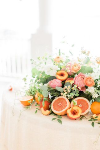 Playful Peach + Citrus Summer Wedding reception table flower centerpiece idea using a mix of fruits and floral arranagements in orange, coral and peach with hints of fresh vibrant greenery.   https://www.confettidaydreams.com/playful-peach-citrus-summer-wedding-ideas/  #peachwedding #coralwedding #summerwedding #citruswedding #whimsicalwedding #romanticwedding Grapefruit Wedding Decor, Citrus Floral Arrangement, Spring Centerpiece Ideas, Italian Event, Summer Wedding Ideas, Summer Wedding Reception, Fruit Wedding, Citrus Wedding, Fruits And Flowers