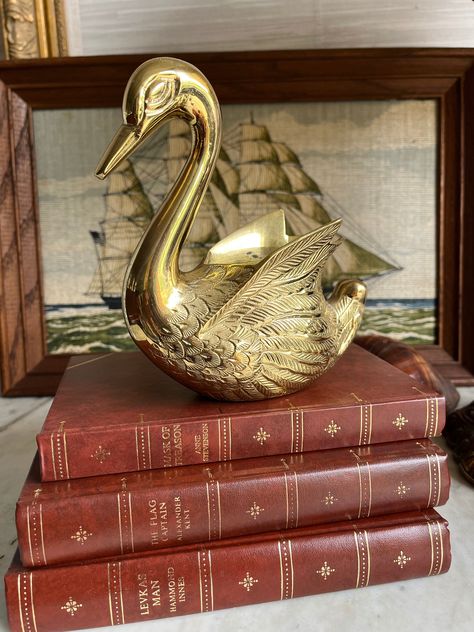 This elegant brass swan planter is a beautiful addition to any decor. Apart from housing plants like air plants and succulents, which require minimal drainage, this swan planter can serve multiple decorative purposes. It makes a unique pen or utensil holder for a chic office or kitchen. Alternatively, use it as a sophisticated candy dish or a holder for various trinkets and jewelry. Its gleaming finish and graceful design will elevate the ambiance of any space, making it versatile for both pract Dark And Moody Bedroom, Brass Swans Decor, Swan Bookends, Vintage Brass Decor, Swan Planter, Brass Frog, Brass Animals Vintage, Brass Ornaments, Brass Swan