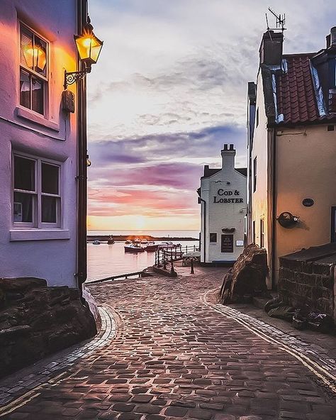 Are you an early morning person...or a night owl? Love that burst of dawn colour as the sun rises over the North Sea at Staithes in gorgeous Yorkshire. Ahhh... a glorious glowing lamp, old cobbles and piping hot fresh fish and chips soaked in lip-smackin' salt and vinegar awaits! That Cod and Lobster pub looks especially inviting too. Love Ireland Landscape, English Village, Holiday Places, Yorkshire England, England Travel, Beautiful Places To Travel, North Yorkshire, Antalya, Cyprus