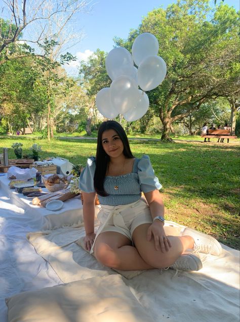 Mulher de blusa azul e short branco sentada na toalha de piquenique ao lado de comidas e balões. Ao redor, árvores e muito gramado. Dia ensolarado de primavera no parque. Look Picnic No Parque, 16 Birthday, Bruno Mars, Photos Ideas, The Park, Books