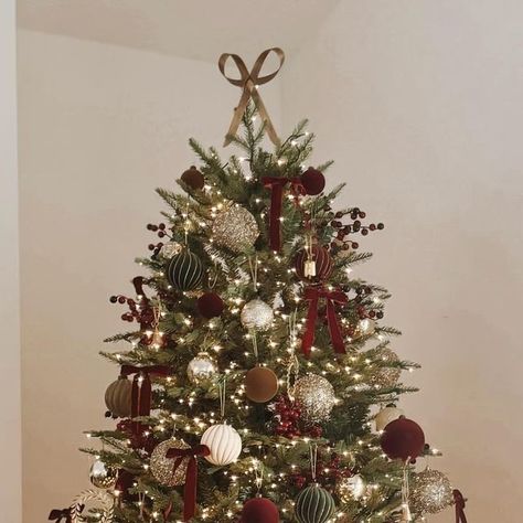 Diana Fernandez on Instagram: "As promised, here is a still photo of my 2024 Christmas tree ❤️

also sharing some sources and answering frequently asked questions below: 

🌲 Bows - Amazon. I bought one pack of the 1” size and used about 20. They came with little zip ties, which made the process a lot easier.
🌲Berries - used approximately 15 of the smaller picks and 8 of the larger picks and broke those into smaller pieces. 
🌲Tree topper - @mcgeeandco 
🌲Nutcracker- recently found it at @target and gave him a makeover with some gold spray paint I had on hand and hot glued one of the bows from the tree to tie it all together. 

Process: I started with the larger ornaments, which in my case were the tinsel ones. I used two packs of those. Then I added all of the mercury glass, velvet bulbs Burgundy And Gold Flocked Christmas Tree, Velvet Bow Tree Topper, Gold Bow Christmas Tree, Christmas Tree With Picks, Burgundy And Gold Christmas Tree, Christmas Tree With Tinsel, Small Apartment Christmas Tree, Christmas Tree With Coloured Lights, Wine Christmas Tree