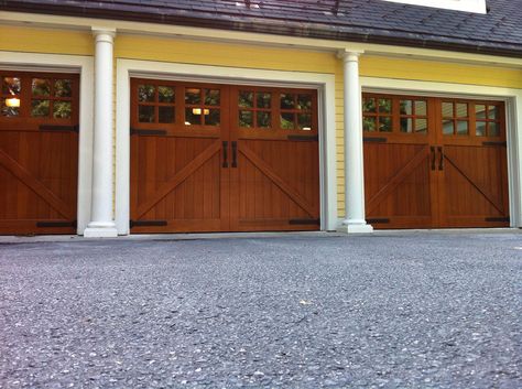 Clopay Reserve Collection custom wood carriage house garage doors.Love the warmth and contrast of the stained wood against the yellow house. Installed by Marathon Door and Glass. www.clopaydoor.com Yellow House Garage Door Colors, Walnut Color Garage Door With Deep Water Paint, English Oak Garage Doors, Wood Carriage Garage Doors, Deep Brown Garage Door, Brown Garage Door, Stamped Carriage House Garage Door, Custom Wood Garage Doors, Carriage Style Garage Doors