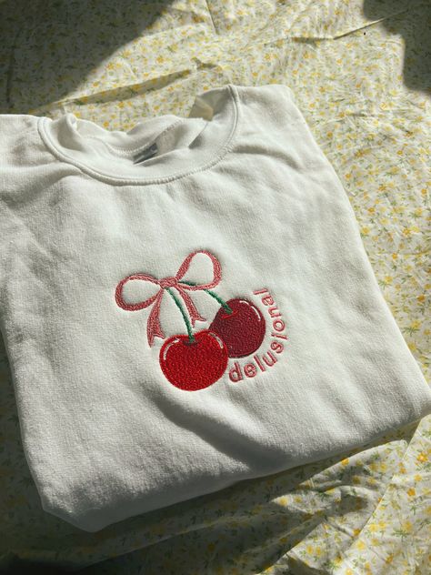 A white crewneck with a 3x5 cherry with a pink bow with the words delusional in pink. Cherry Gift Ideas, Sweater Shirt Outfit, Outfit Ideas Shirt, Etsy Sweatshirts, Shirt Outfit Ideas, Cherry Sweater, Shirt Design Ideas, White Crewneck, Fun Sweatshirts