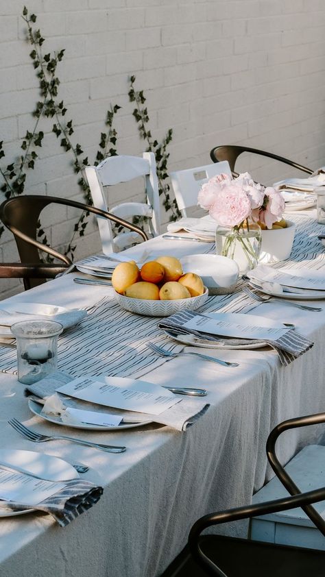 1.An outdoor tablescape set with grey and blue tablecloth + napkins. Pink flowers and bowls of lemon served as centerpieces. 2. A menu on top of a grey and white striped napkin and white plate 3. Charcutierie boards and floral napkins 4. Another table angle 5. Greeting table with flowers, lemons in crates and vases, a lamp, a rolling pin. 30th Birthday Dinner, Nancy Meyers Movies, My 30th Birthday, Nora Ephron, When Harry Met Sally, Dinner Party Themes, Birthday Dinner Party, Nancy Meyers, The Lane