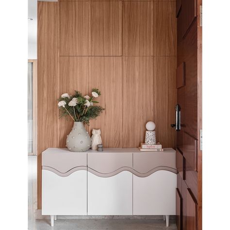 Keeping in line with the Japandi aesthetic, we created a minimalist cabinet with defining waves and colour blocked it. The chic cabinet added charm to this compact entryway with a wooden wall panel behind it acting as a great backdrop. The wall panel apart from adding aesthetically, also masks an unsightly MCB box.   #studioipsa #foyer #foyerdesign #foyerdecor #interiordesign #interiorstyling #homedecor #foyerdesign #foyerenterance #foyerconsole #compactenterance Foyer Console Table Decor, Foyer Console Table, Foyer Console, Japandi Aesthetic, Minimalist Cabinet, Console Table Decorating, Wooden Wall Panels, Foyer Decor, Foyer Design