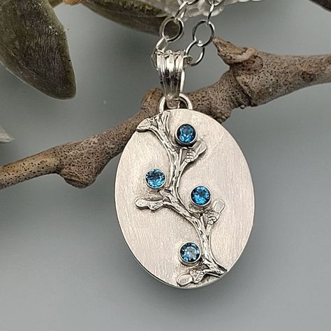 Inspired by a rambling hedge of wild blueberries, this dainty London blue topaz necklace combines the perfect amount of rustic detail dotted with cool blue stones. Hand-wrought from recycled sterling silver, an oval pendant is set with four tiny London blue topaz stones along a vertical rambling vine that is lightly oxidized to show its organic detail. The nature-inspired blue topaz pendant suspends freely from your choice of an 18 or 20-inch sterling silver cable chain. Blueberry Bramble, Stone Settings Jewelry, London Blue Topaz Necklace, Pmc Jewelry, Diy Jewelry Pendants, Silver Metal Clay, Bezel Jewelry, Silver Jewelry Diy, Handmade Silver Jewellery