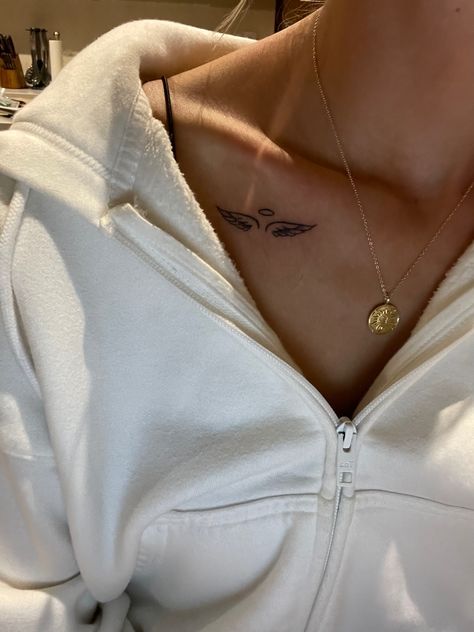 Woman wearing a white hoodie with gold necklace and tattoo Angel Tattoo On Collarbone, Angel Wings Tattoo On Collar Bone, Womens Angel Wing Tattoos, Collar Bone Tattoo Angel Wings, Angel And Halo Tattoo, Halo With Angel Wings Tattoo, Tatoos Angel Wings, Angel Wings Tattoo Above Elbow, Wings Tattoo Collar Bone