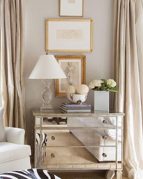 Elegant bedroom features stacked abstract nude sketches placed over a mirrored dresser topped with a crystal baluster lamp and a Nate Berkus Ikat Bowl flanked by windows dressed in champagne colored silk curtains. Mirrored Dresser, Bedroom Nightstands, Transitional Bedroom, Nate Berkus, Zebra Print, Dresser, Champagne, Curtains, Bowl