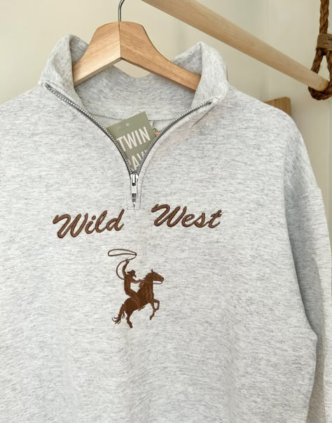 We sell primarily on our website and offer free shipping options. TwinRavenCo Giddy-up with these cozy Wild West quarter-zip sweaters. Fleece-lined, unisex, pre-shrunk, and are resistant to pilling- let's get to the point, these sweaters are durable and are sure to keep you comfy. Recommend to size-up if in-between sizes. * Check out our socials for discounts, new releases, and to see how we run our shop: TwinRavenCo We use the highest quality, sustainable thread on all of our products- check ou Country Tops For Women, Western Quarter Zip, Thrifted Western Outfits, Western Hippie Fashion, Western Fall Fashion, Giddy Up, Western Sweaters, Embroidery Stabilizer, Casual Country Outfits