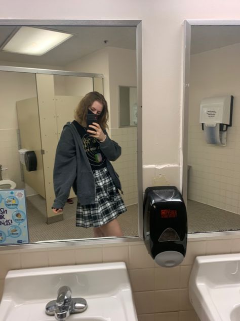 a teenage girl is wearing a plaid skirt, black band tee, oversized gray zip-up hoodie, and white sneakers Hoodie Outfit With Skirt, How To Style Gray Zip Up Hoodie, Dark Gray Zip Up Hoodie Outfit, Style Grey Zip Up Hoodie, Skirt And Zip Up Hoodie Outfit, Oversized Gray Zip Up Hoodie Outfit, Plaid Skirt With Hoodie, Gray Zip Up Hoodie Outfit, Grey Plaid Skirt Outfit