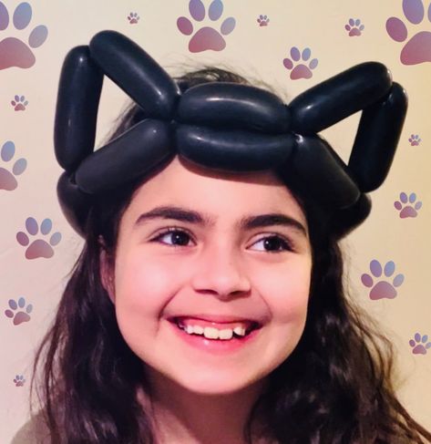 A little girl wears a black balloon hat, twisted to look like cat ears or bat ears. Balloon Animal Tutorial Easy, Balloon Animal Hat, Balloon Hats Easy, Balloon Hats How To Make, How To Make Balloon Animals Step By Step, Balloon Animal Ideas, Ballon Character, Halloween Balloon Animals, Balloon Animal Tutorial