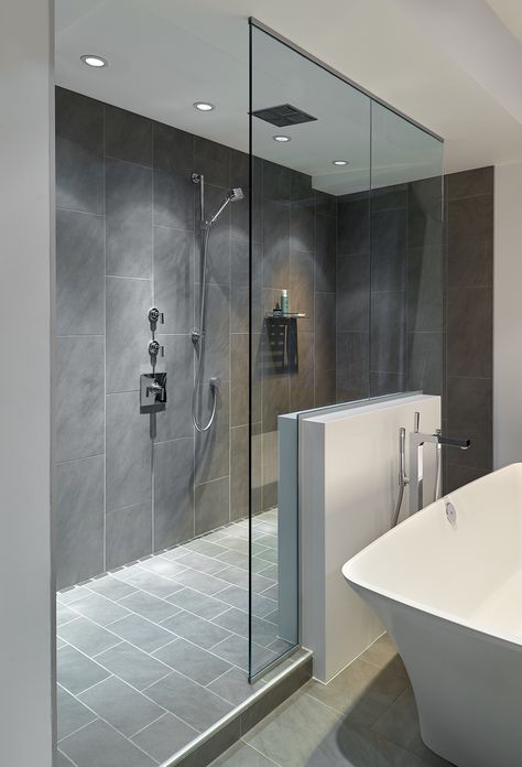 Large walk-in doorless shower with gray slate tiles and a floating glass wall creates a gorgeous modern look in this bathroom. Soaking tub provides a beautiful place for peaceful relaxation. Homestead Bathroom, Gray Bathrooms, Gray Shower Tile, Small Tile Shower, Glass Showers, Large Tiles, Gambling Art, Doorless Shower, Slate Tiles