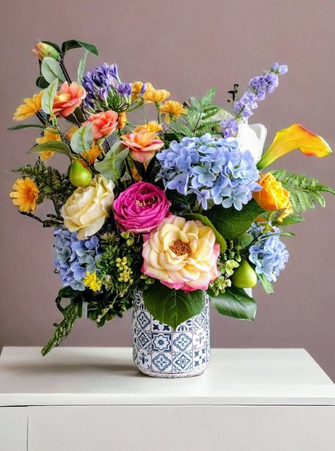 Beautiful realistic real touch and silk floral arrangement in a blue and white talavera style ceramic vase. Blue and light green real touch hydrangeas, realistic pear branches, roses, calla lilies and other wild flowers mixed with abundant foliage, arranged and nestled in a beautiful talavera style ceramic vase. It is a beautiful real like arrangement to show off in any season of the year. This arrangement is a unique piece that has been delicately handcrafted with love and dedication and represents hours of design and elaboration. At the time of purchase it will be carefully packed so that it arrives safely to its destination. I would like to mention however that should any unfortunate mishap occur during shipping, your purchase is 100% insured against any damage or loss. If you wish to s Floral Arrangements With Blue Hydrangeas, Blue And White Ceramics, Flower Arrangements Hydrangeas, Grandparents Memorial, Blue Floral Arrangements, Hydrangea In Vase, Cranberry Appetizer, Wild Flower Arrangements, Flower References