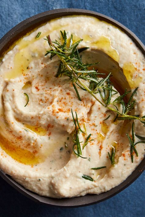 Roasted Garlic and White Bean Dip With Rosemary Recipe - 1  head garlic 1  teaspoon, plus 5 tablespoons olive oil 2  (15-ounce) cans white beans, like cannellini, Great Northern or navy beans, drained and rinsed 3  tablespoons lemon juice (from 1 lemon) 1  tablespoon roughly chopped fresh rosemary leaves, plus 1 full sprig ¼  teaspoon black pepper 1  pinch of cayenne, plus more for garnish (optional) 1  tablespoon hot water 1 ¼  teaspoons kosher salt White Bean Dip Recipe, White Bean Hummus, Rosemary Recipes, Bean Dip Recipes, White Bean Dip, Whipped Feta, Bean Dip, Nyt Cooking, Thanksgiving Appetizers