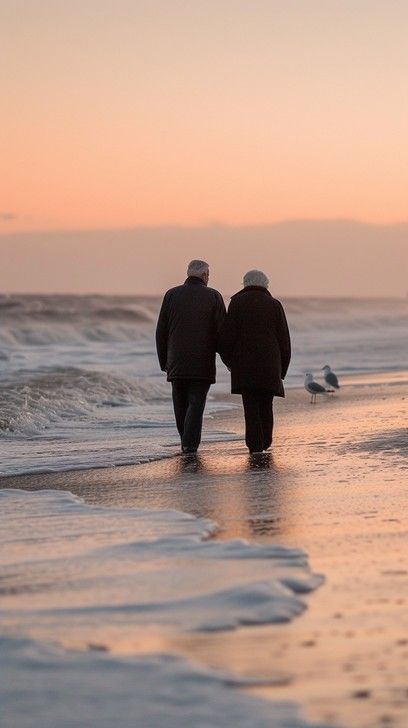 StockCake An elderly couple holds hands as they walk along the beach at sunset, a serene moment. Man And Woman Walking Together, Elderly Aesthetic, Lovers At The Beach, Happy Old Couple, Couple Walking On Beach, Portugal Apartment, Couples Vision Board, Vision Board Photos, Couple Holding Hands