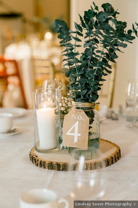 Mark and Rebecca's wedding in Alton, Ontario - WeddingWire.ca Modern Rustic Theme Wedding, Candle And Mason Jar Centerpieces, Wedding Table Decor With Greenery, Sage Green And Grey Wedding Centerpieces, 1 Tier Wedding Cake Rustic, Greenery In Mason Jars, Mason Jar Table Numbers, Dried Eucalyptus Centerpiece, Rustic Wedding Table Decor Mason Jars