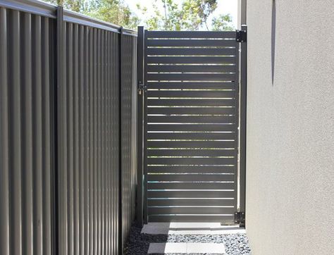 It's cool to see a metal gate like this. I love how the slats on the door or horizontal, but those on the actual fence are vertical. That's the sort of style I love. Colorbond Fence, Slat Fencing, Fencing And Gates, Steel Gates, Pedestrian Gate, Metal Garden Gates, Modern Gate, Aluminium Gates, Side Gates