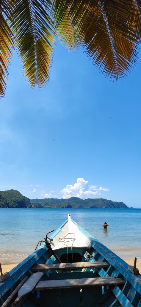 Un bote mirando desde la arena al mar azul y calmado. En el cielo azul algunas ramas de palmeras verdosas y anaranjadas. Venezuela Wallpaper, Venezuela Aesthetic, Latina Wallpaper, Venezuela Beaches, Gap Year Travel, Vision Board Pics, Trip To Colombia, Exotic Places, Ocean Wallpaper