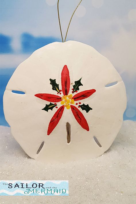 "This real Florida sand dollar has been hand painted with a bright red poinsettia surrounded by holly leaves. Use it as a holiday ornament, give as a gift to someone special, keep as a reminder of a special vacation, or simply hang on your window to enjoy year-round to bring the beach to you! We individually hand paint each of our sand dollars so that no two are exactly the same. The ornaments are finished at the top with a luminous gold cord for hanging or displaying. They measure 3.5\" to 4.5\ Painted Sand Dollars Christmas Ornaments, Painted Sand Dollars Christmas, Oyster Angel, Sand Dollar Decor, Sand Dollar Ornaments, Florida Crafts, Pansy Art, Painted Sand Dollars, Sand Dollar Craft