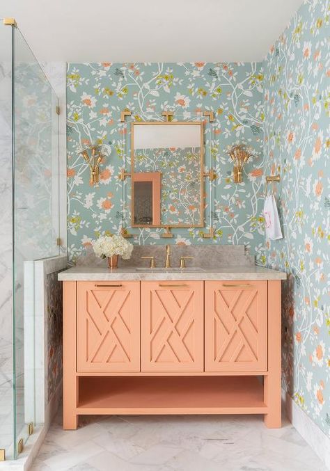 Beautiful blue and orange floral wallpaper covers the walls of this small bathroom boasting an orange sherbert washstand accented with brass hardware and a brass faucet kit fixed beneath a brass and lucite mirror flanked by brass sconces. Florida Bungalow, Peach Bathroom, Houston Interior Designers, Orange Bathrooms, Bathroom Color Schemes, Best Outdoor Furniture, Bathroom Color, Old Florida, Blue Bathroom