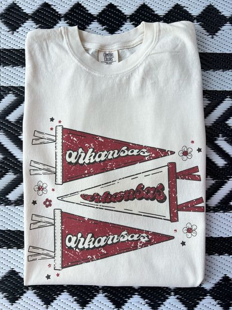 New product- Vintage Arkansas Pennant Shirt! Get ready to show off pride with our Vintage Pennant Shirt, a must-have for all fans! This unique design combines a vintage style with the fierce spirit of fans, creating a shirt that stands out from the crowd. Each shirt is meticulously printed by me using high-quality materials on a Comfort Colors shirt, known for its exceptional comfort and durability.  Available in sizes S to 3X, we've got you covered regardless of your preferred fit. The shirt features a classic crew neck and short sleeves, making it suitable for year-round wear. The flattering silhouette ensures a comfortable and stylish fit for both men and women. This design is an ideal choice for game days, tailgating parties, alumni events, or simply strolling around campus. Note: As e College Tee Shirts, Highschool Sports Shirts, Game Day T Shirts, Retro Baseball Shirt, Game Day Tops, Sports Sweatshirt Designs, Cute College Shirts, High School T Shirt Designs, Vintage Baseball Shirt