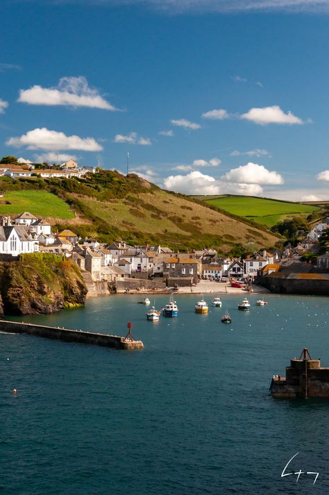 The quaint fishing village of Port Isaac in Cornwall, UK, is more widely known as Portwenn from the television series Doc Martin. The harbour walls offer stunning views of the Celtic Sea, and also of the village itself. Here we look back towards Port Isaac from the headland on the west side of the village. Country Living Uk, England Aesthetic, Port Isaac, English Architecture, Seaside Village, Cornwall England, Old Port, Cloudy Day, Fishing Villages