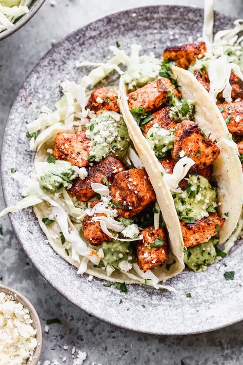 Stuffed with buttery blackened salmon bites and shredded cabbage then drizzled with a luscious Jalapeño cilantro Crema and crumbled Cotija cheese, our salmon tacos are sure to hit the seafood spot. Blackened Salmon Bites, Cilantro Crema, Salmon Tacos Recipe, Salmon Bites, Mexican Side Dishes, Salmon Tacos, Blackened Salmon, Shredded Cabbage, Tacos And Burritos