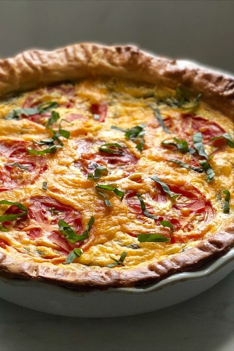 A quiche dish with round tomato slices laid in cheddar cheese and lightly topped with basil. Tomato Basil Mozzarella Quiche, Quiche Recipes Savory, Cheese And Tomato Quiche, Tomato Basil Tart Recipe, Tomato Mozzarella Quiche, Tomato Basil Quiche Recipes, Quiche Meal Ideas, 3 Cheese Quiche 12 Tomatoes, Tomato Basil Pie Recipe