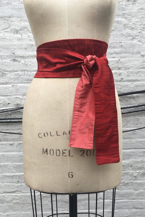 This modern interpretation of an obi sash is made in two colors of silk shantung. Shown in a rich ruby red reversing to vibrant coral. The sash provides an instant update to your wardrobe - add to a basic black dress or pair it with a tunic tee and jeans. It can be worn wrapped and tied in the front (as shown) or tied in the back. It's the ultimate must-have accessory! Widest part approx. 3 1/2" Tie ends approx. 2 1/4" Available in 3 lengths: 80" long - fit up to a 32" waist when wrapped & tied Belts Aesthetic, Obi Sash, Hex Girls, Basic Black Dress, Star Wars Halloween, Ball Gown Skirt, Beautiful Skirts, Suspender Belt, Fabric Belt