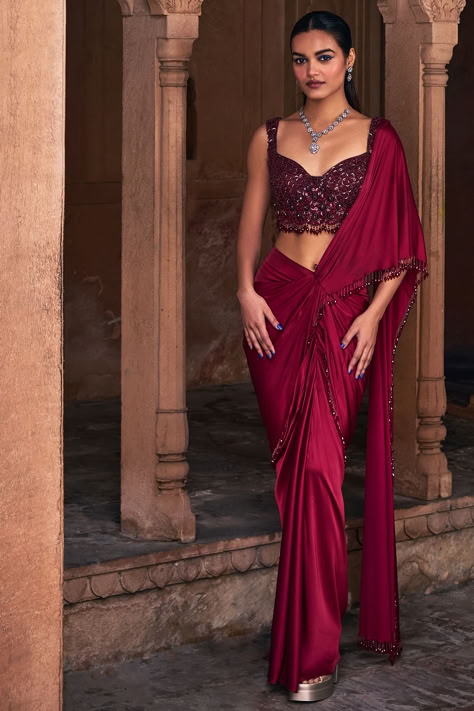 Maroon Draped Skirt Saree Set that captivates with its elegance. The eye-catching saree is crafted in tulle and armani satin with tassel details. It is paired with an embroidered blouse. For weddings or festive occasions. New Indian Fashion Finds redefine festive style with our innovative fusion designes.   #Perniaspopupshop #womenswear #ethnic #whatiworewastrending #ppuslove #sareeset #armanisatin #tulle #festivewear #sareeforwomen #printedsaree #weddingwear #skirtsaree Fusion Saree, Skirt Saree, Drape Sarees, Fusion Wear, Sharara Suits, Letters Design, Saree Designs Party Wear, Satin Saree, Draped Skirt