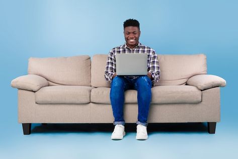 Cool young black guy sitting on sofa wit... | Premium Photo #Freepik #photo #online-work #remote-work #person-computer #person-working Guy Sitting, Work Remote, Black Guy, Happy Guy, Man Sitting, Young Black, Online Work, Premium Photo, Remote Work