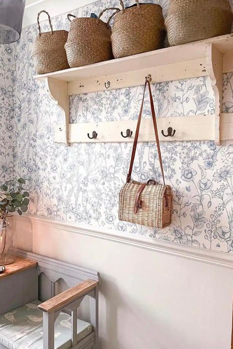 Narrow hallway with beige lower half and blue and white floral wallpaper above, featuring shelving for baskets and hooks for bags and coats. Explore creative hallway wallpaper ideas for limited spaces. Hallway Decorating Wallpaper, Dado Rail Bedroom, Bold Hallway, Dado Rail Hallway, Hallway Wallpaper Ideas, Narrow Hallway Decor, Cottage Hallway, Stairs And Hallway Ideas, Wallpapered Entryway