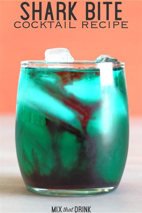 The Shark Bite cocktail recipe gets its name from the way the drops of grenadine look like blood in greenish-blue water. This one always gets a laugh at parties, especially Halloween parties. This is a fun, fruity drink that impresses guests and tastes delicious. #drinkrecipes #rumdrinks #rumcocktails #partydrinks #cocktailrecipes #partycocktails Kraken Drinks Recipes, Uv Blue Drinks Recipes, Shark Bite Drink, Spiced Rum Drinks, Grenadine Cocktail, Blood In The Water, Alcoholic Treats, Easy Alcoholic Drinks, Hey Bartender