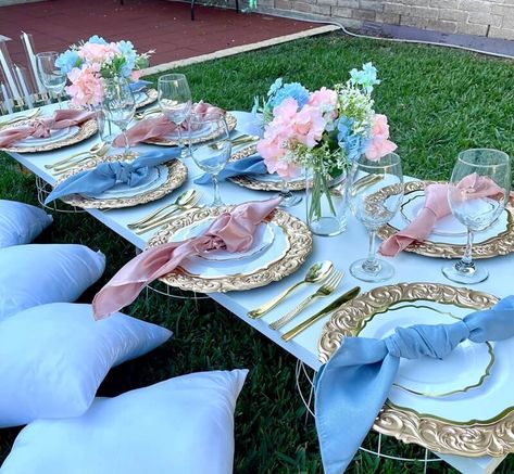 Set up a fabulous tablescape at your garden party with glamorous decorations. Spread a grass rug and place a few cushions alongside your low-height table. Display pink & sky blue hydrangeas along with white baby breaths in clear glass vases placed on the table to add a refreshing vibe to the decor. Glam up the place setting with gold chargers, gold scalloped rim plates, gold cutlery, and pink & sky blue napkins for an eye-catching tabletop decor. Pink White And Blue Party Decorations, Blue And Pink Table Decor, Pink And Blue Decor Party, Pink And Blue Party Decor, Pink Blue Birthday Party, Pink And Blue Tea Party, Blue And Pink Table Setting, Princess Table Setting, Pink And Blue Birthday Party