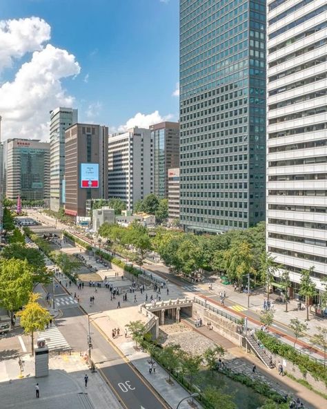 This is a photo of a city street with tall buildings. The image includes tags such as outdoor, cloud, tower block, metropolitan area, commercial building, tree, building, urban area, sky, metropolis, downtown, mixed-use, condominium, urban design, cityscape, skyline, daytime, skyscraper, road, apartment, corporate headquarters, street, tower, and city. Japan Tokyo Wallpaper, Cheonggyecheon Stream, Tokyo Wallpaper, Korea Store, Seoul Korea Travel, Cool City, Beautiful Blue Sky, South Korea Seoul, Tall Buildings