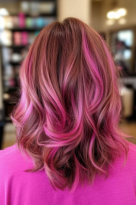 Woman with shoulder-length brown hair styled with pink highlights. Copper Hair Pink Highlights, Wolfcut Pink Highlights, Bright Pink Highlights In Brown Hair, Cotton Candy Pink Highlights In Brown Hair, Pink Chunky Highlights In Brown Hair, Neopolitan Hair Highlights, Red Hair With Pink Highlights, Color Safe Shampoo, New Hair Trends