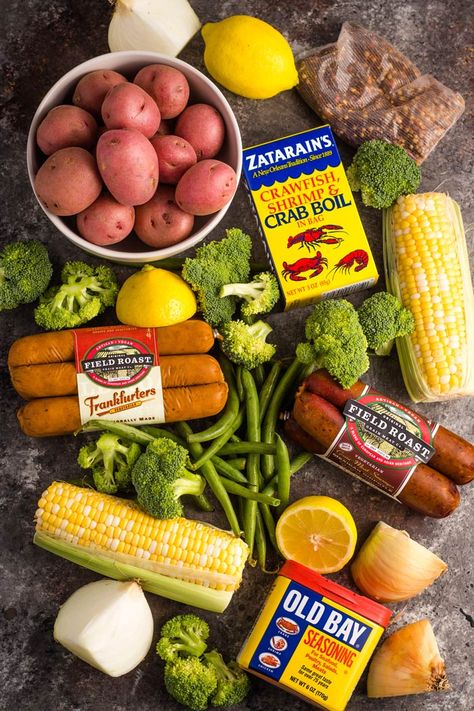 Ingredients for a vegan boil laid out on a surface - red potatoes, corn on the cob, broccoli florets, green beans, vegan sausage, and seasoning. Vegan Boil, Green Beans Vegan, Crab Boil Recipe, Vegan Cookout, Appetizers Seafood, Vegan Cajun, Vegan Crab, Seafood Boil Recipes, Boiled Food