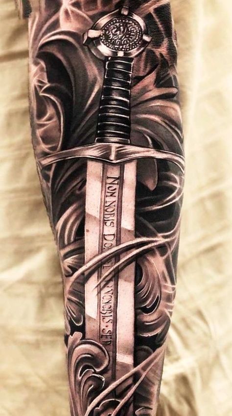 A sword tattoo is one of the most iconic designs. But only a few people know the true meaning behind it. Dive into our research to become a real sword tattoo lord. Tato Nama, Armor Of God Tattoo, Armour Tattoo, Stammestattoo Designs, Warrior Tattoo Sleeve, Viking Warrior Tattoos, Shield Tattoo, Gladiator Tattoo, Soldier Tattoo