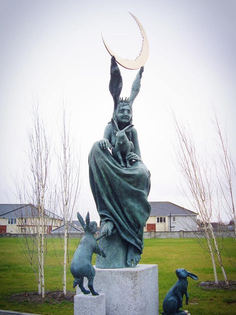 Athy, Co. Kildare, Ireland.  The Hare Queen is a bronze sculpture 2.5 meters high which sits on a Wicklow grant base.  the sculpture by Fidelma Massey was designed to celebrate the hares which co-exist on the college site. The Hare Queen is the mother of the hares, their deity/protectress - one of Mother Nature's many guises.  She holds the crescent moon in her ears.  Hares have always been associated with the Moon. Fidelma Massey, Pagan Spirituality, City Winery, Rabbit Sculpture, How To Make Drawing, Gothic Horror, Courtyard Garden, Woodland Creatures, Bronze Sculpture