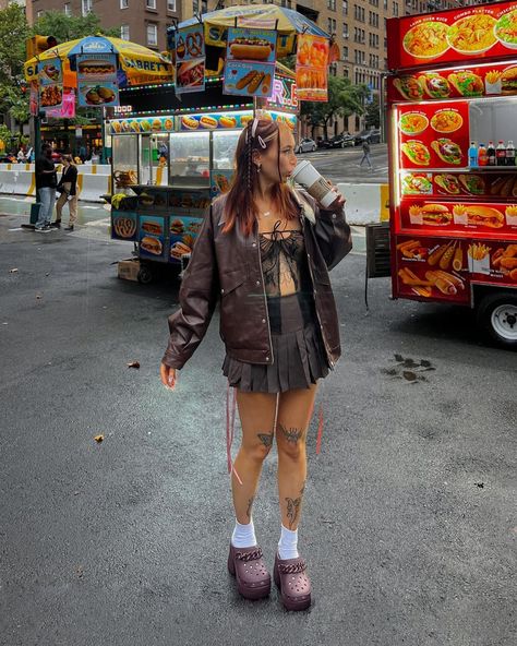 The carrousel of photos shows @sheisnevil wearing a brown outfit with heeled crocs and a ribbon hairstyle. First is a head-to-toe picture of her sipping in a Starbucks cup in the streets of New York City. Second is a close-up on her nails and crocs. Third is her standing in front of a mammoth fossil in the American Museum of Natural History. Siren Clog Crocs, Croc Heels Outfit, Crocs Heels Outfit, Siren Crocs Outfit, Crocs Siren Clogs Outfit, Brown Crocs Outfit, Crocs Outfit Fall, Siren Clog Crocs Outfit, Crocs Clogs Outfits Style