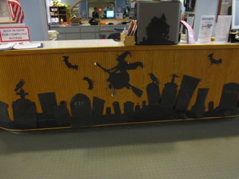 Front of circulation desk decorated for halloween, use black bulletin board paper for cutouts. Decorate Office For Halloween, Front Desk Halloween Decorations, Fall Office Decorations Cubicles, Desk Halloween Decorations, Library Halloween Decorations, Halloween Cubicle Decor Contest, Halloween Desk Decorations For Work, Halloween Cubicle Decor, Cubicle Halloween Decorations