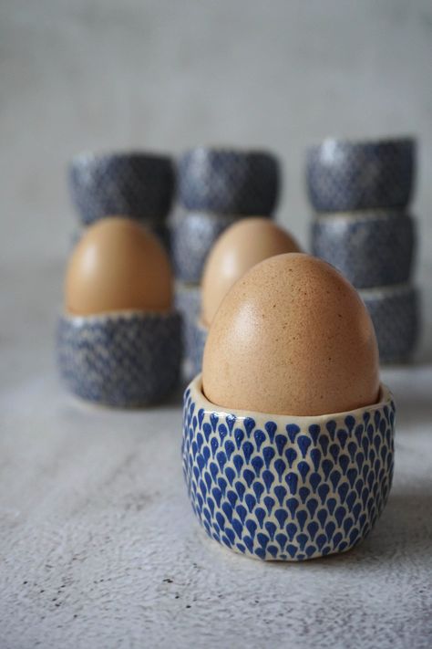 These egg cups are perfection for your Sunday Brunch or an upcoming Easter celebration! Each one of them  slowly engraved with blue engobe and then covered in transparent glaze. Each item is made totally by hand from start to finish and this makes them unique and one of the kind. All of my ceramics are made by using white clay. I do my best to make them all even however small differences between picture and the item you purchase may vary. As well some color, height and width variations should be Ceramic Egg Cup, Ceramic Egg Holder, Easter Pottery, Egg Cups Holders, Ceramic Egg Cups, Ceramic Egg, Cup Handmade, Pottery Handbuilding, Keramik Design