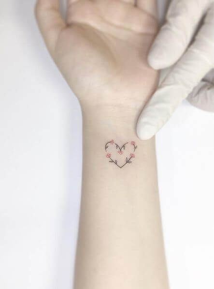 This heart tattoo for women is perfect for those women who do not want to get a lot of ink but would still like an elegant tattoo that just exudes class. The heart's outline is formed by a vine with five strategically placed flowers in pink. It looks very classy and works like dynamite. #tattoofriday #tattoos #tattooart #tattoodesign #tattooidea Heart Tattoo Wrist, Tattoo Wrist, Tattoos Geometric, Heart Tattoos, Tattoos For Daughters, Trendy Tattoos, Small Tattoo, Rose Tattoos, Sleeve Tattoo