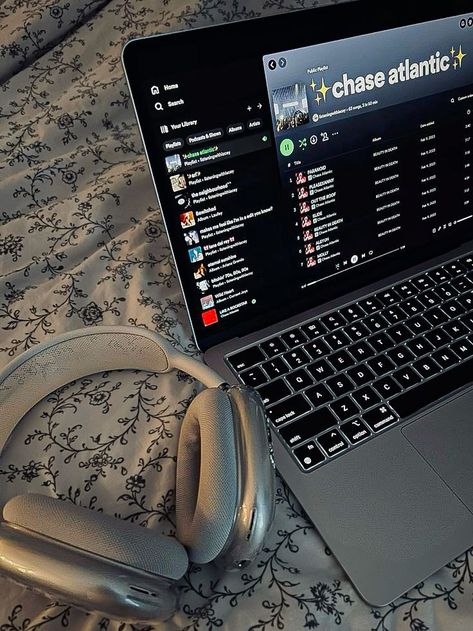 A close-up of a laptop displaying a Chase Atlantic playlist on Spotify, resting on a floral-patterned bedsheet with a pair of silver over-ear headphones beside it Chaseatlantic Aesthetic, Macbook Aesthetic Desktop, Spotify Laptop, Aesthetic Electronics, Mac Wallpaper Desktop, Sleepover Stuff, Macbook Aesthetic, Music Corner, Aesthetic Laptop