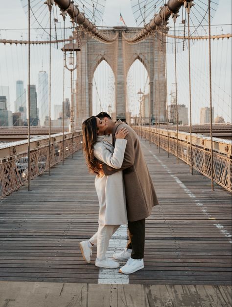 Man kissing woman on the cheek for their engagement photos taken in brooklyn at the brooklyn bridge in new york city Nyc Couples Photoshoot Winter, New York Couple Outfit, New York Winter Engagement Photos, Engagement New York, Brooklyn Bridge Picture Ideas Couple, New York Couple Photography, Nyc Winter Couple Photos, Brooklyn Bridge Couple Photoshoot, New York City Couple Pictures