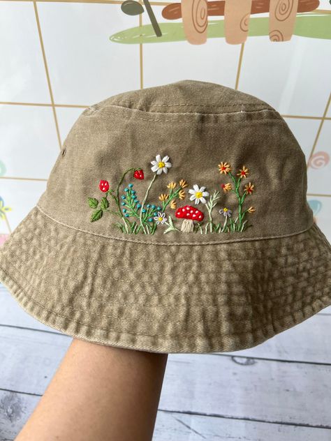 We can make other flowers and add personalization. If you have any requirement, please note it in the order or message us. Thank you! 📍Product name: Hand Embroidered Floral Bucket Hat Design: hand embroidered daisy flowers, wild flowers, mushroom, sunflower Size: one size fits most, hat circumference: 54-58cm Material: cotton absorbs sweat well, cool so bring a sense of comfort to the wearer. Good and durable material. Products are hand-embroidered entirely from Vietnamese craftsmen. Each stitc Cute Fall Hats, Floral Sewing Projects, Embroidered Sun Hat, Cute Little Embroidery Designs, Embroidery Baseball Caps, Bucket Hat Embroidery Ideas, Embroidered Ball Cap, Embroidery Hat Ideas, Hat Embroidery Ideas