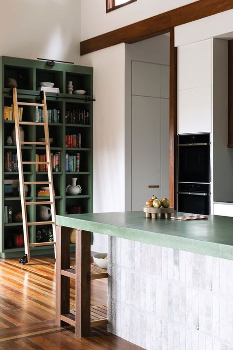 A green and timber kitchen with a coloured-concrete island bench and ceiling beams. Concrete Island, Concrete Kitchen Island, Concrete Tile Floor, Brunswick House, Kitchen Splashback Tiles, Ceiling Shelves, Timber Kitchen, Timber Shelves, Kitchen Island Bench