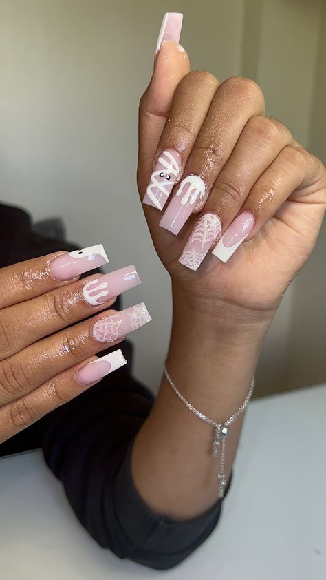 Light pink nails with French tip design on thumb and pinky finger with the animated ghost on the left index finger and a animated mummy on the right index finger to drip sign on the middle fingers and two glittery cobwebs on the ring fingerS French Tips Autumn, Mummy French Tip Nails, Pink And White Ghost Nails, White French Tip Halloween Nails, White Drip Nails, Pink And White Halloween Nails, White Spooky Nails, Spiderweb French Tip Nails, Mummy Nails Halloween